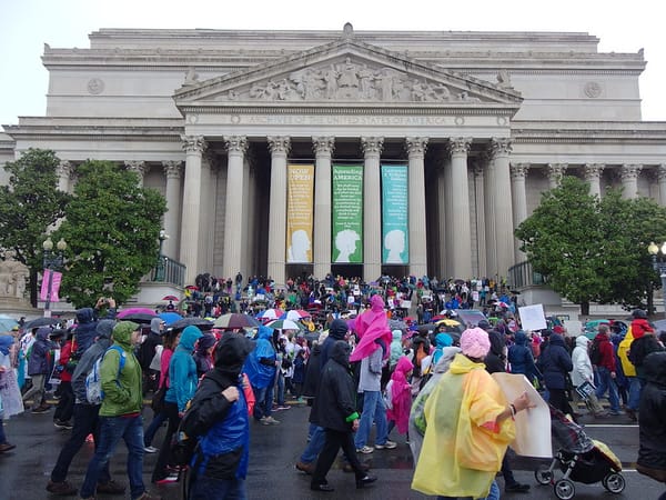 The Archives of the United States of America building, with a full street of pedestrians in front.